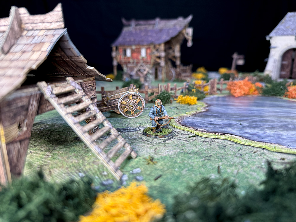 A lone Bolt Action German soldier is shown on Battle Systems fantay terrain featuring the Outbuilding, Barn and Chapel sets.