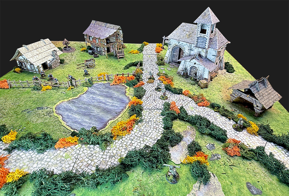 Bolt Action German and American troops fight on a battlefield using the Battle Systems Fantasy Chapel and Barn, Roads, Lakes, Cottage, and Outbuilding.